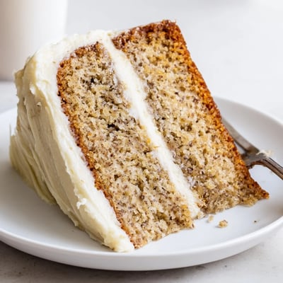 Brown butter banana cake topped with pillowy cream cheese frosting served on a white platter